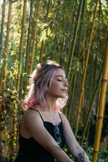 Close-up of young woman with closed eyes sitting in forest