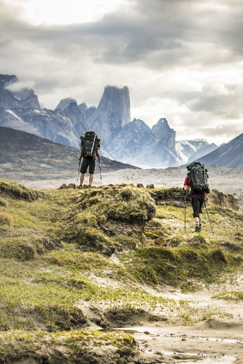 Two climbers hike through dramatic mountain pass.