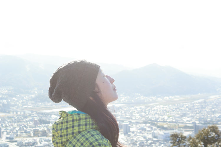 Rear view of woman looking at mountains against sky. 