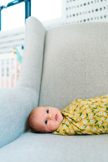 Closeup portrait of a newborn baby girl swaddled in a rocking chair