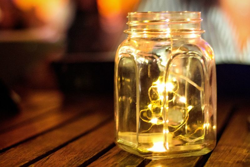 Close-up of illuminated lighting equipment in jar on table