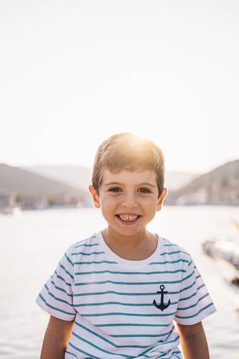 Portrait of smiling boy at beach against clear sky