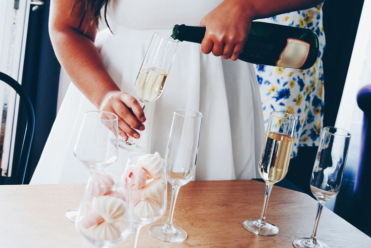 Midsection of woman pouring champagne in flute during birthday party