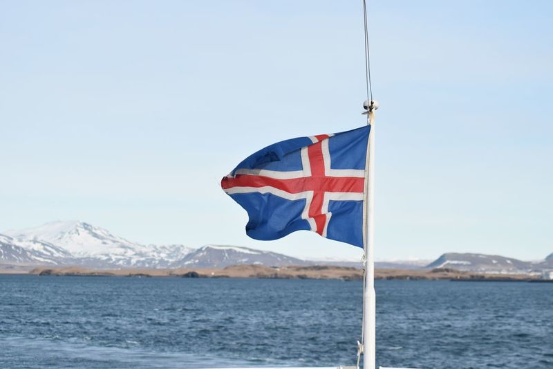 Flag flags on sea against clear sky