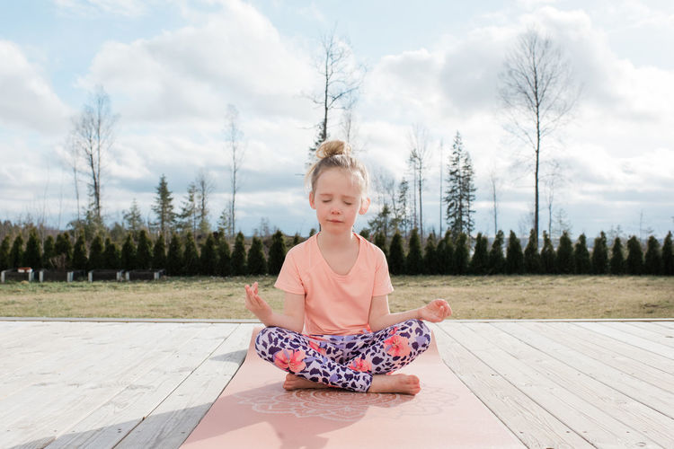 Young girl meditating doing yoga in her back yard at home