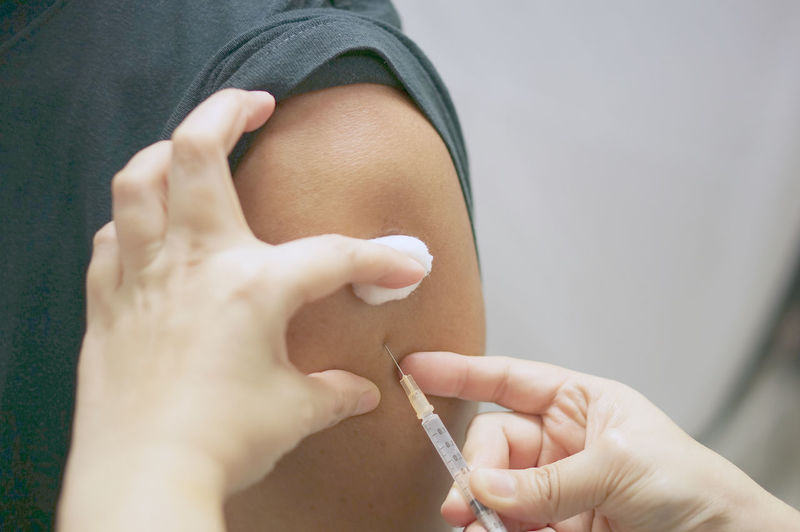 Cropped hands of doctor injecting on patient hand