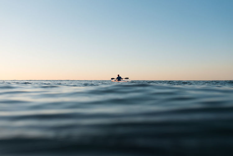 Man boating on sea during sunset