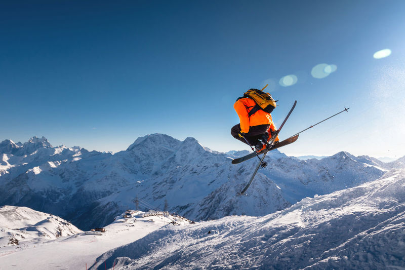 The skier jumps on the background of the blue sky and snow-capped mountains. freestyle skier