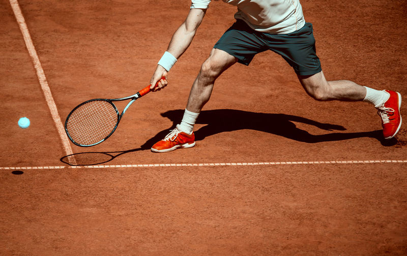 Low section of man playing tennis in court