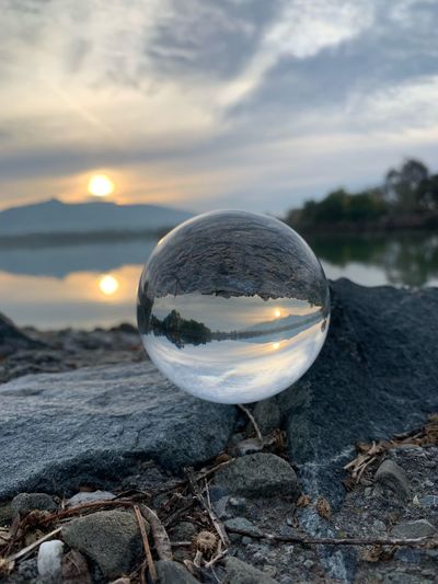 Crystal ball on rock at lake during sunset