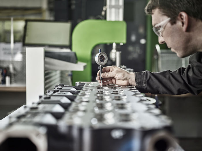 Worker in metalworking factory controlling cylinder head