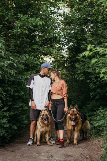 Couple with dog standing against trees