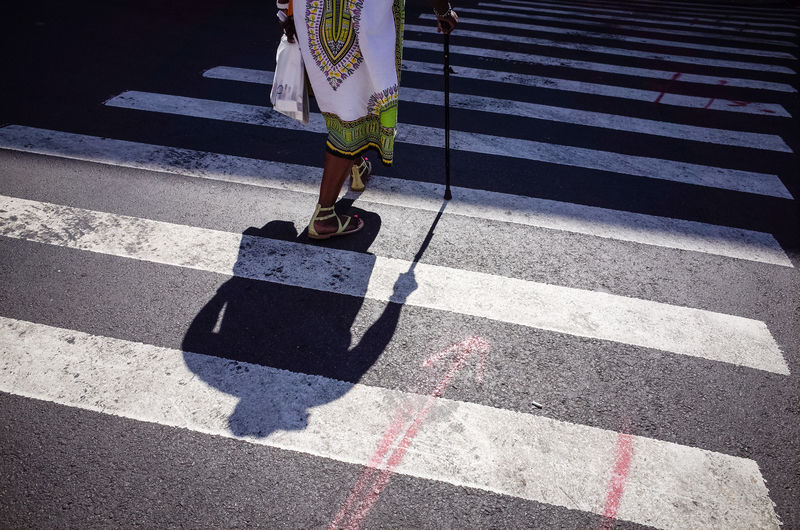 Low section of woman crossing road