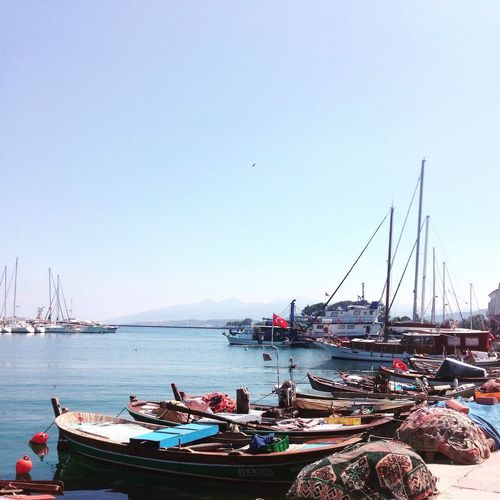 Boats moored in river against clear sky on sunny day