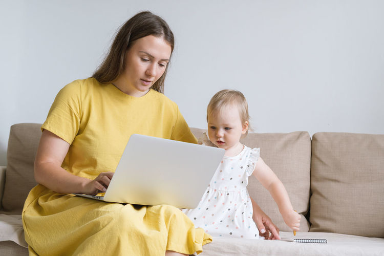 Curious child looking at mother laptop display. mother using gadgets for baby entertainment