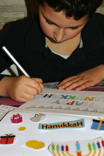 Close-up of boy writing on paper at home