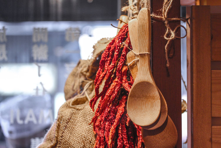 Close-up of wooden spoons with red chili peppers hanging in store