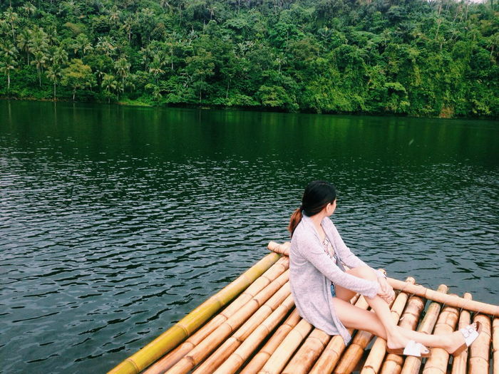 Woman looking away while sitting on raft at lake