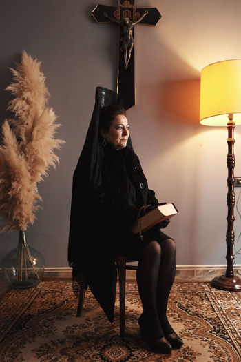 Nun praying against cross at home