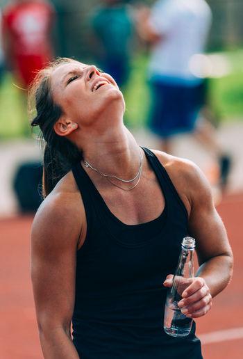 Tired woman having water on running track