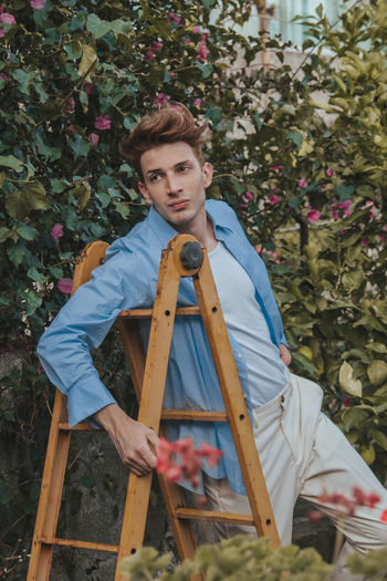 Portrait of young man sitting on plant