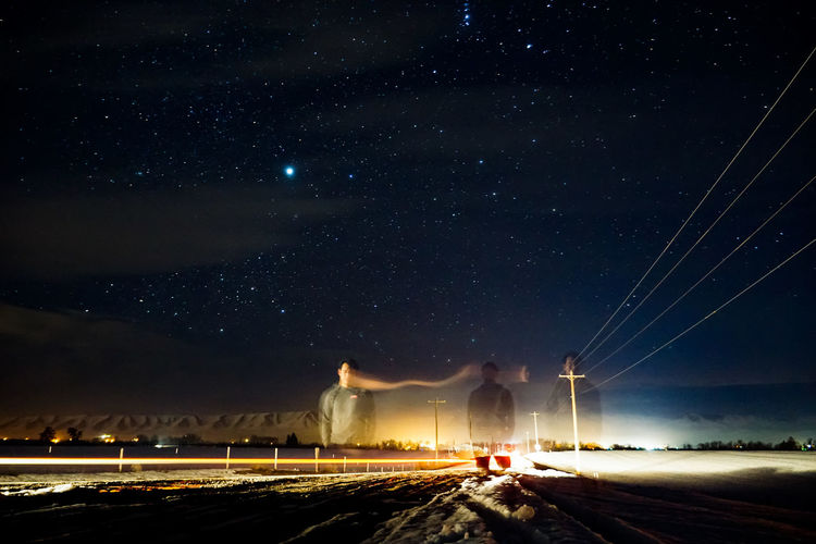 Multiple exposure image of man standing on street against star field at night