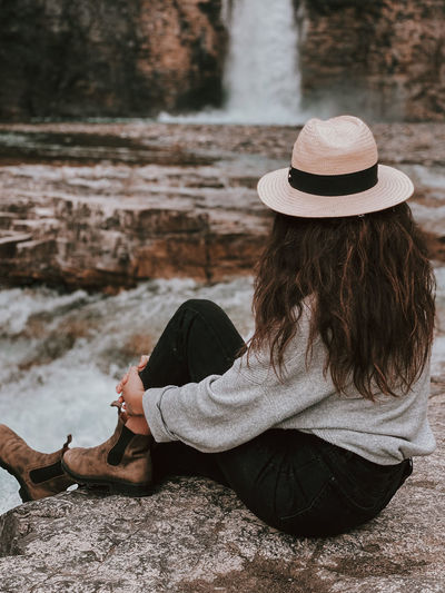 Woman wearing hat sitting outdoors