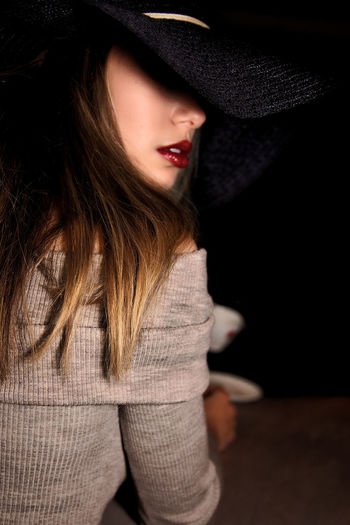 Teenage girl wearing hat looking away against black background