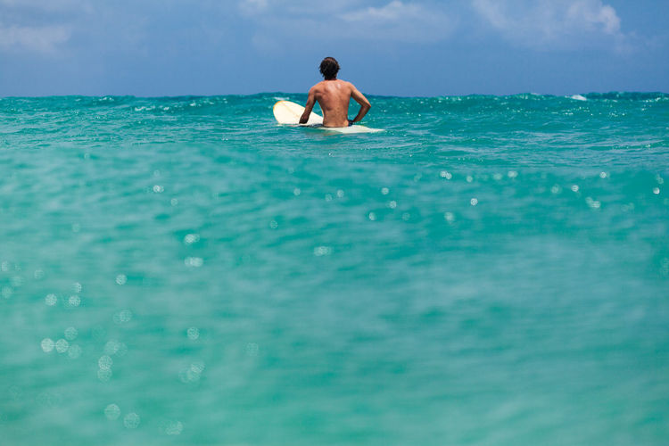 Rear view of man surfing on sea