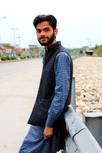 Portrait of young man standing against river