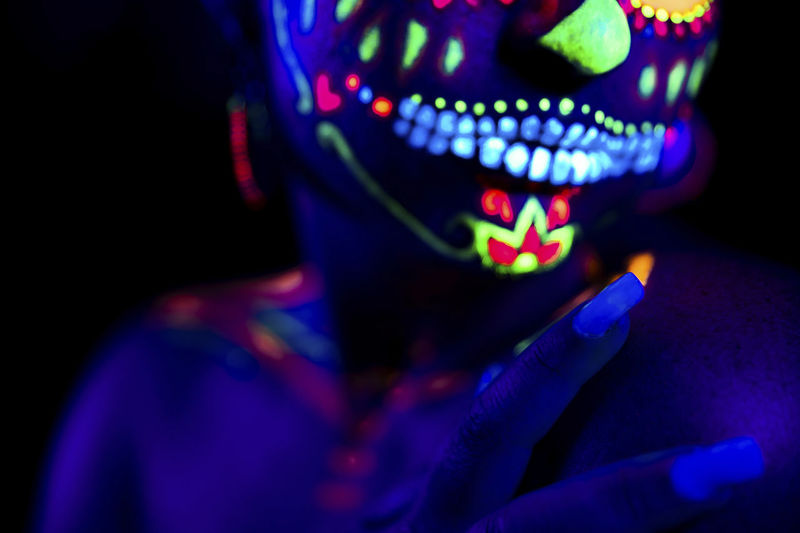 Anonymous female in multicolored masquerade mask with flowers on head on halloween night