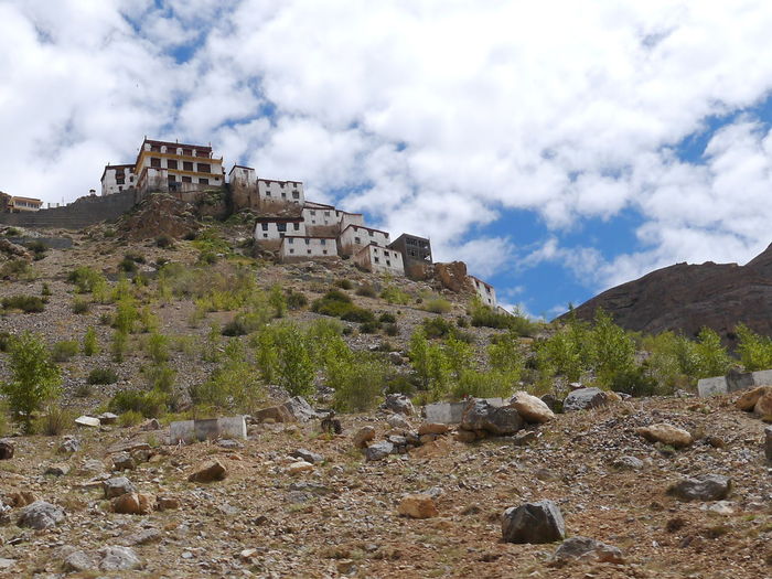 Low angle view of houses on hill against cloudy sky