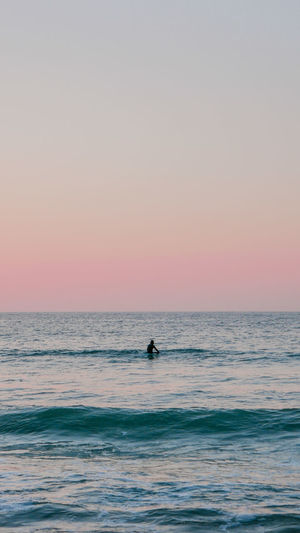 Scenic view of alone surfer and clear sky during sunset in basque country