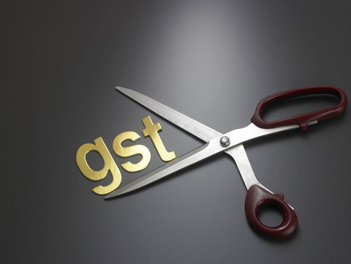 Close-up of gst text with scissor on gray background