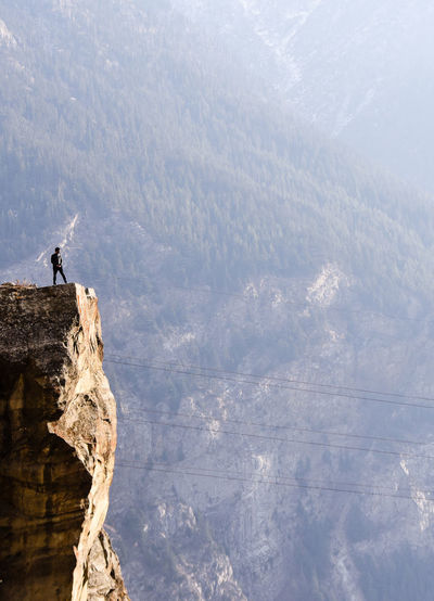 Man standing on cliff against trees