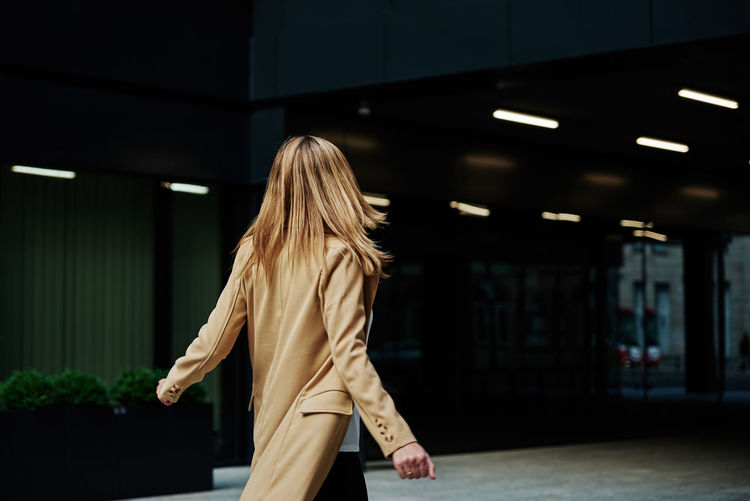 Woman in coat walks at city stret