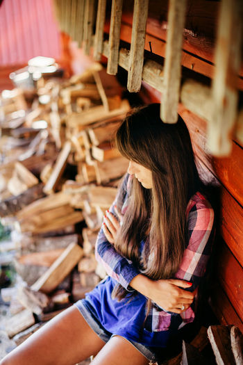 High angle view of woman sitting by stacked logs
