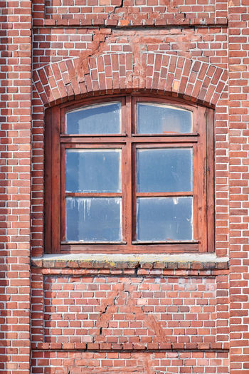 Arched glass window on old red brick wall. vintage window in wooden frame on red brick building wall