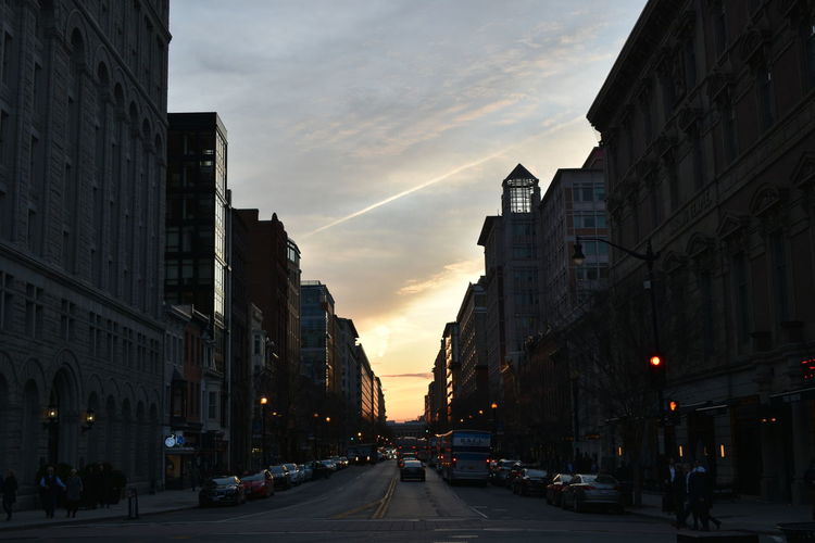 View of city street and buildings at sunset
