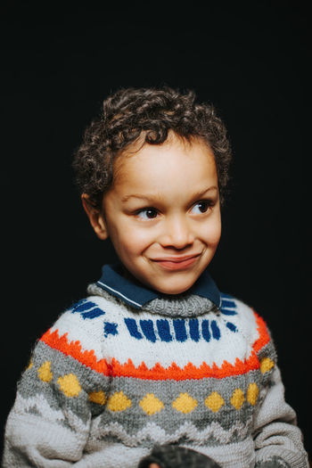 Portrait of smiling boy against black background