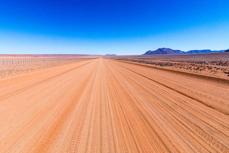 Scenic view of desert against clear blue sky