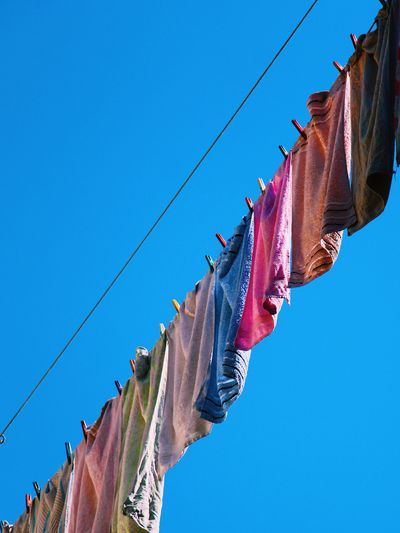 Low angle view of towels drying against blue sky