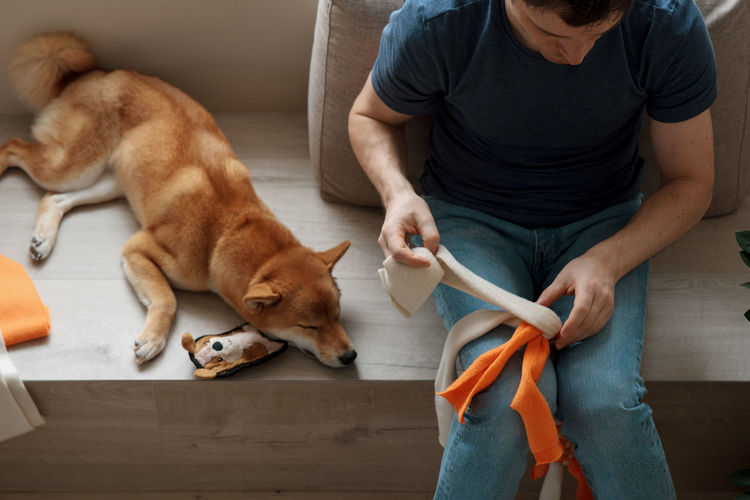 Adult man making diy homemade educational toys for dogs using a tutorial from the internet
