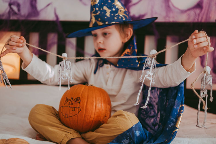 Cute little caucasian boy in a halloween costume with big orange pumpkin jack-o-lantern.
