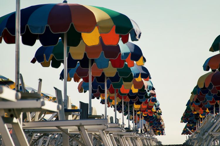 Low angle view of multi colored beach umbrellas hanging against sky