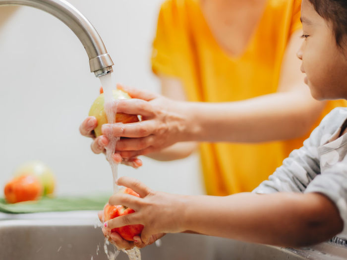 Mother and daughter at home washing apples