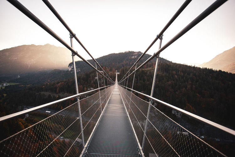 Long empty footbridge against clear sky during sunrise