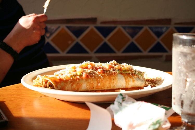Midsection of person having burrito in restaurant
