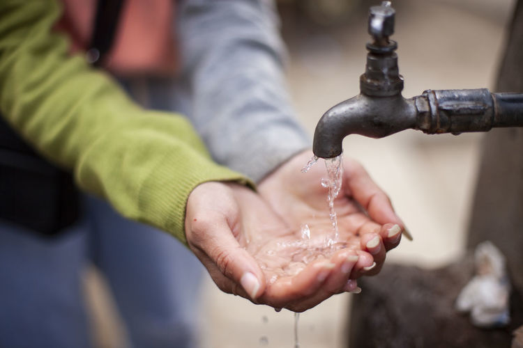 Midsection of woman collecting water from tap