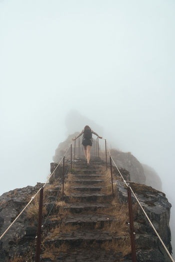 Man on steps against sky during foggy weather